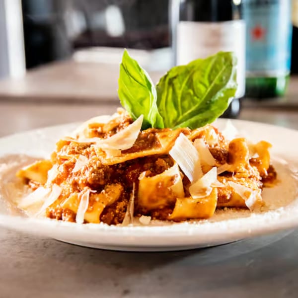 Rocco's Cucina & Bar's Italian pasta with meat sauce, parmesan, and basil on a white plate.