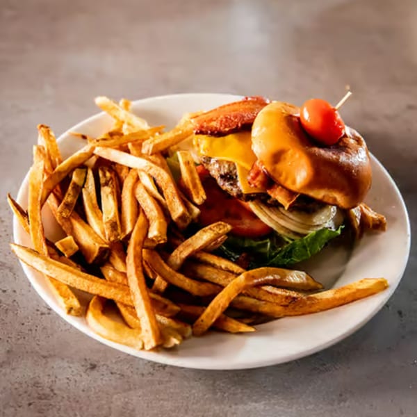 A Rocco's burger with bacon, cheese, lettuce, tomato, onion, and a side of fries.