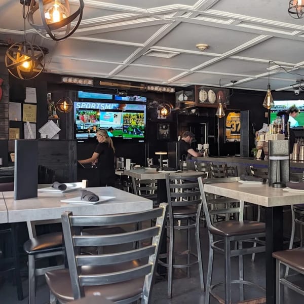 Interior of Rocco's Cucina & Bar with high-top tables, bar seating, and multiple TVs showing sports.
